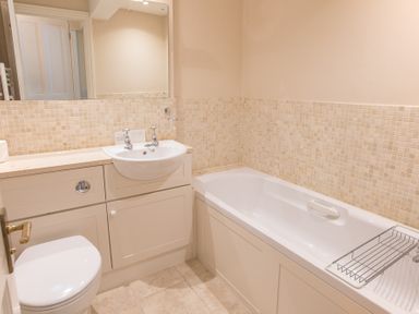 A bathroom with a toilet sink bathtub and tiled walls at Jot Cottage in Salcombe