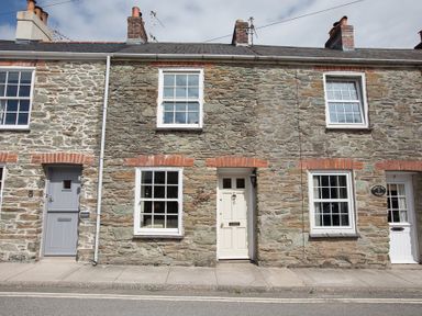 A row of stone cottages with white and gray doors and windows along a street at Jot Cottage in Salcombe