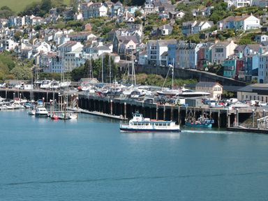 A harbor with boats docked near colorful houses on a hillside at Kings View in Dartmouth