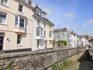 A street with multiple two to three story houses next to a stone wall at Kings View in Dartmouth