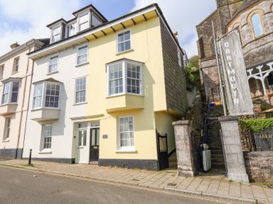A street view of connected houses with bay windows and a stone stairway beside a building with a dartmouth sign at Kings View in Dartmouth