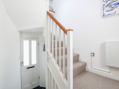 A staircase with beige carpet and white railing next to a white front door with frosted glass panels at Kings View in Dartmouth