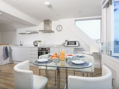 A kitchen with white cabinets a glass dining table with croissants and for breakfast at Kings View in Dartmouth