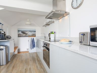 A kitchen with white countertops stainless steel oven a toaster microwave and a painting of a boat at Kings View in Dartmouth
