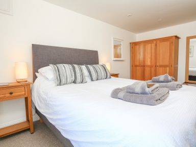 A bedroom with a bed with pillows and folded towels bedside tables with lamps a wardrobe and a mirror at Kings View in Dartmouth