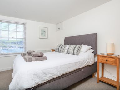 A bedroom with a double bed with striped pillows and folded towels beside a window at Kings View in Dartmouth