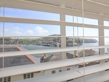 A view of a coastal town with boats on the water through window blinds at Kings View in Dartmouth
