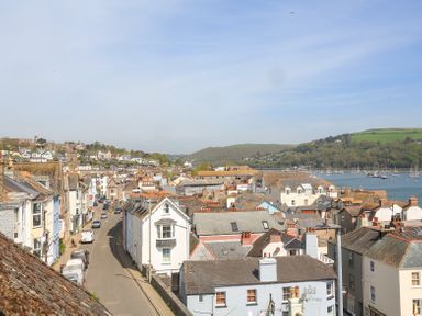 A view of a town with buildings a road with parked cars hills and a body of water with boats at Kings View in Dartmouth