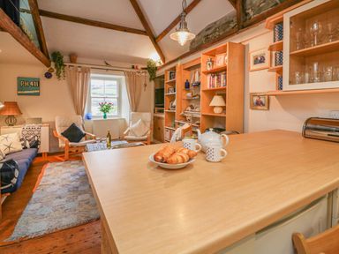 A living room with chairs a wooden table and shelves with books and decor at Lee Shore in Salcombe