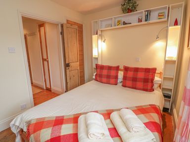 A bedroom with a double bed red plaid pillows and a folded blanket at Lee Shore in Salcombe