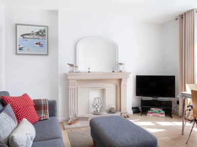 A living room with a fireplace television sofa and cushions at Lower Fernlea in Salcombe