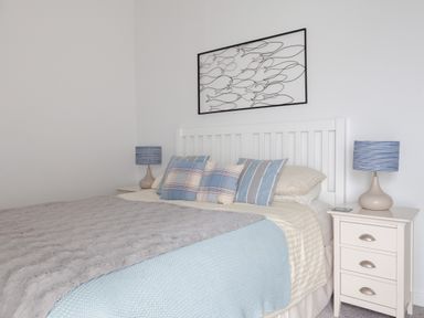 A bedroom with a bed with pillows and two bedside tables with lamps at Lower Fernlea in Salcombe