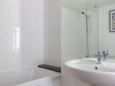 A bathroom with a bathtub shower combination and a sink with a chrome faucet at Lower Fernlea in Salcombe