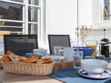 A breakfast table with basket of pastries bowls glasses and juice pitcher at Lower Fernlea in Salcombe