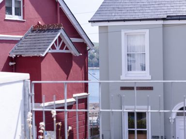Two houses with a view of water and a boat through a gap at Lower Fernlea in Salcombe