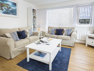 A living room with two beige sofas and a white coffee table on a blue rug at Leeside in Dartmouth
