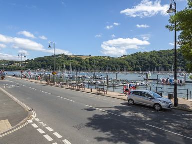 A road next to a marina with boats and a hillside in the background at Leeside in Dartmouth