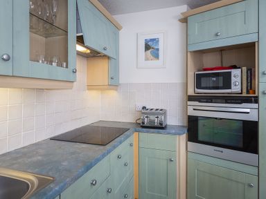 A kitchen with green cabinets a toaster a microwave an oven and a framed picture on the wall at Leeside in Dartmouth
