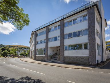 A street view of a multi-story building with stairway entrance and windows at Leeside in Dartmouth