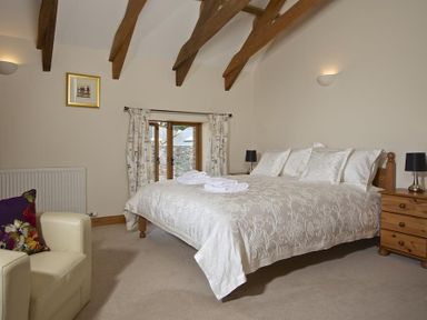 A bedroom with a bed framed by wooden beams and white bedding at Meadow View in Modbury