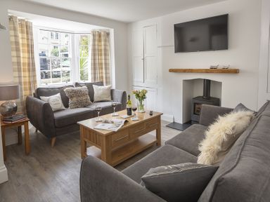 A living room with two gray sofas a wooden coffee table and a wall mounted tv at The Old Wash House in Dartmouth