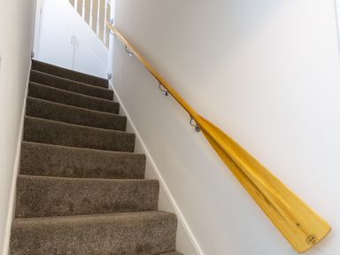 A carpeted indoor staircase with a wooden handrail and white walls at The Old Wash House in Dartmouth