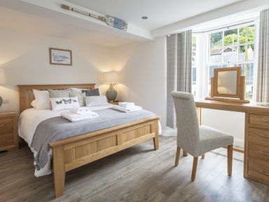 A bedroom with a wooden bed and desk near a window at The Old Wash House in Dartmouth