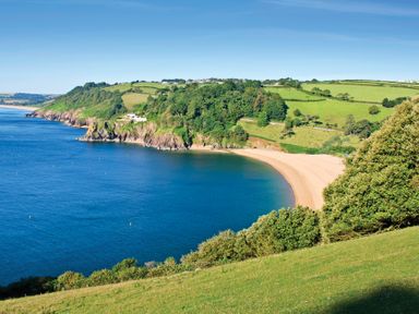 A coastal landscape with a sandy beach blue water and green hills at The Old Wash House in Dartmouth