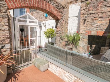 An outdoor seating area with stone walls and a glass partition at The Old Wash House in Dartmouth