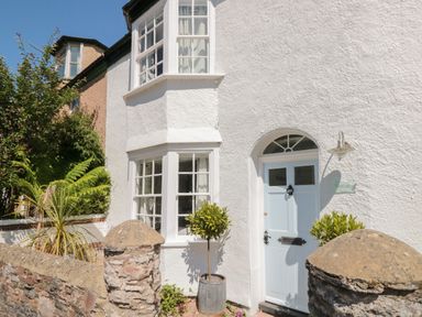 The exterior of a white house with a pale blue door and bay windows at The Old Wash House in Dartmouth