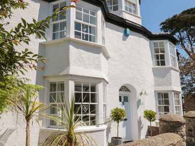 White exterior of a house with bay windows and potted plants at The Old Wash House in Dartmouth
