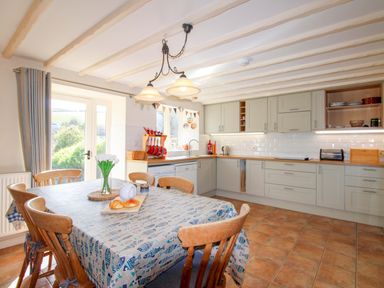 A kitchen with a table and chairs at Orchard Barn Salcombe