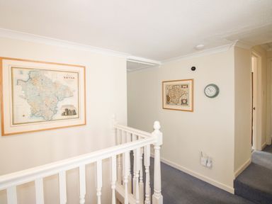 A hallway with maps on the wall and a clock at Orchard Barn Salcombe