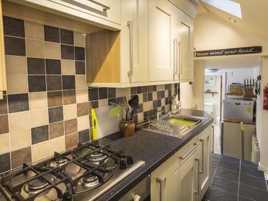 A kitchen with a gas stove sink and wall cabinets at Pixie Cottage in Dartmouth