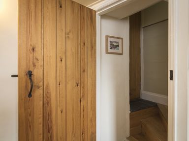 A wooden door next to a small staircase with a framed picture on the wall at Pixie Cottage in Dartmouth
