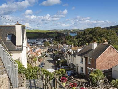 A street with houses and cars with a river and green hills in the background at Prospects in Salcombe