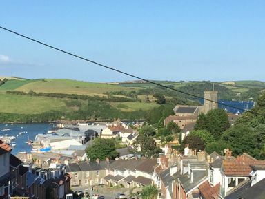 A view of rooftops with a river boats and green hills in the background at Prospects in Salcombe