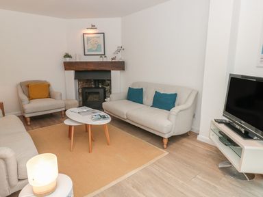 A living room with sofas a fireplace a television and a coffee table at Prospects in Salcombe