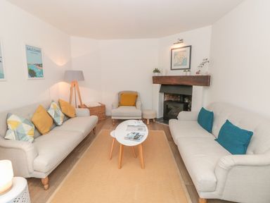 A living room with two sofas a chair a coffee table and a fireplace at Prospects in Salcombe