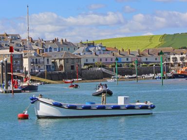 A harbor with several boats on water and houses with a grassy hill in the background at Raleigh House in Salcombe