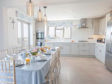 A kitchen with a dining table set for breakfast with bowls cups and orange juice at Raleigh House in Salcombe
