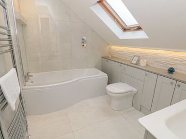 A bathroom with a bathtub toilet towel rack and skylight window at Raleigh House in Salcombe
