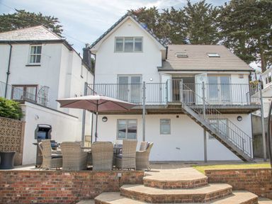 A backyard patio with outdoor dining set and umbrella at Raleigh House in Salcombe