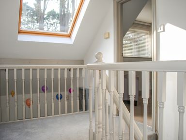 An indoor stairway with white wooden railing and a skylight window above at Raleigh House in Salcombe