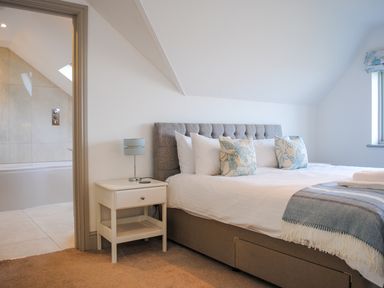 A bedroom with a bed pillows and a bedside table next to a bathroom at Raleigh House in Salcombe
