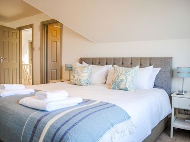 A bedroom with a large bed with white linens and blue patterned pillows at Raleigh House in Salcombe