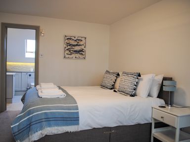 A bedroom with a bed pillows bedside table and a view into a bathroom at Raleigh House in Salcombe