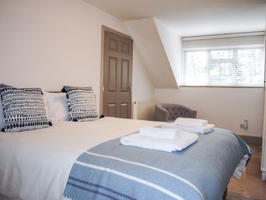 A bedroom with a bed with towels and pillows near a window and a gray door at Raleigh House in Salcombe
