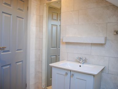A bathroom with a sink cabinet mirror and a door at Raleigh House in Salcombe
