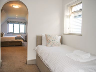 A bedroom with a single bed and an archway leading to another bedroom with a double bed at Raleigh House in Salcombe